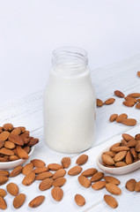 Almond milk in the bottle with nuts on white background