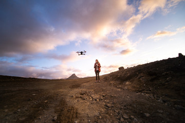Silhouette of woman controlling and piloting drone at sunset