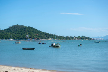 Fototapeta na wymiar Beautiful beach landscape in Brazil. Calm turquoise sea with fishing boats and sailboats moored near the shore. Photo with space for text. Concept of tourism and beach holidays.