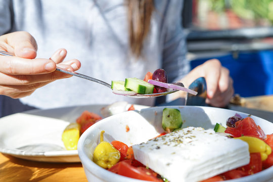 A spoonful of Mediterranean salad, held by a woman