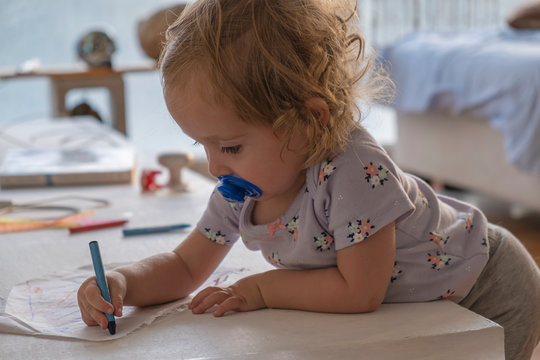 Little girl drawing with colors in the room of the house.