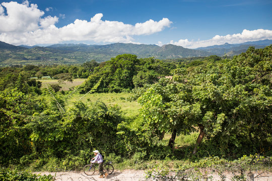 Elderly man pushing bike along dirt road, Guatemala.