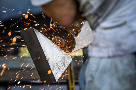 Close-up of worker using angle grinder in a factory