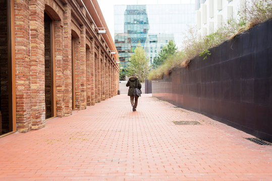 Bearded man walking across pathway holding a take away coffee