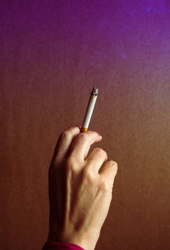 A woman's hand, with a lit cigarette.