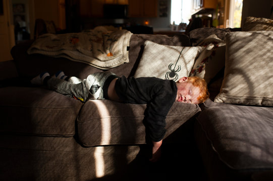 Toddler boy sleeping on his stomach on couch at home in pretty light