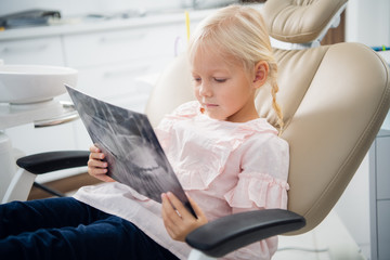 A small girl listening to a doctor, who is showing her her x-ray