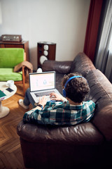 Young man sitting on couch and using notebook