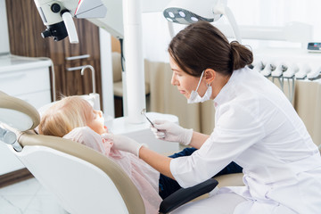 people, medicine, stomatology and health care concept - Image of a little girl having her teeth checked by a female doctor at the clinic