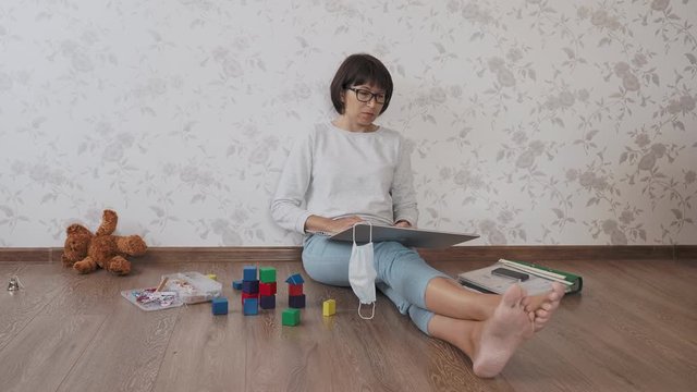 Mom and son sit at home quarantine because of coronavirus COVID19. Mother works remotely among with toys. Self isolation at home.