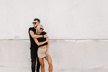 Fototapeta na wymiar Lovely couple outdoor photography smiling and hugging with happy emotion. Street fashion photography outdoor in white background available space for text for advertisement.