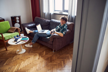 Obraz premium Cheerful young man using laptop at home