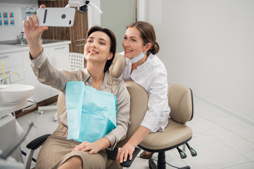 Obraz premium Unusual selfie. Shot of a young woman making a selfie sitting in a dental sitting during her checkup