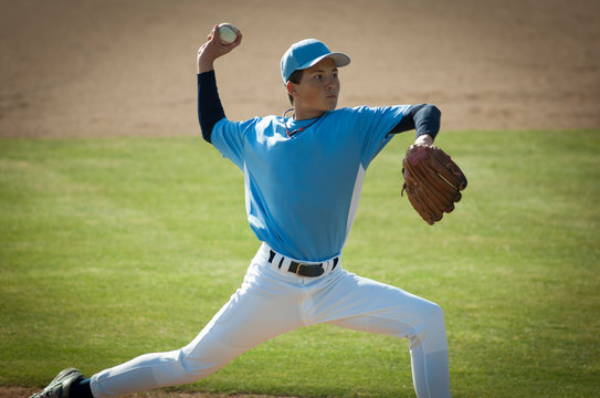 Pitcher in light blue and white jersey during wind up on the mound