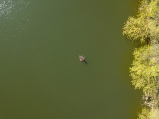 A fisherman on a raft in the middle of a lake. Aerial drone view.