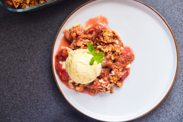 Home cooked Rhubarb and Strawberry crumble from oatmeal and nuts topping and with vanilla ice cream scoops