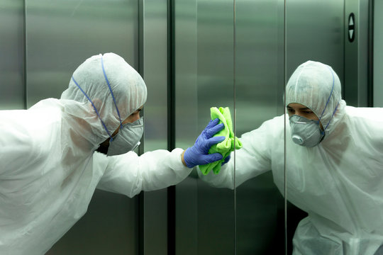 coronavirus. Worker disinfecting hospital elevator to avoid contagion.