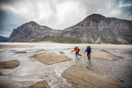 Two backpackers navigate a series of river crossings in Akshayak Pass