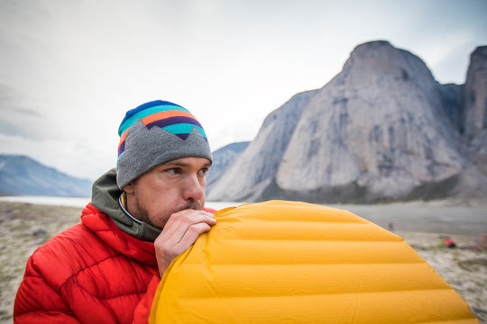 Climber blowing up air mattress while camping in mountains.