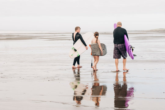 Family walking down the beach with surf and boogie boards