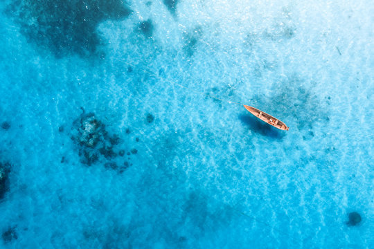 Aerial view of the fishing boat in transparent blue water at sunny day in summer. Top view from above of boat, sandy beach. Indian ocean in Zanzibar, Africa. Landscape with canoe and clear sea. Travel © den-belitsky