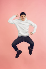 Strong. Caucasian young man's modern portrait isolated on pink studio background. Beautiful male model in high jump. Concept of human emotions, facial expression, sales, ad. Copyspace.