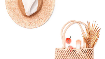 Straw hat, wicker bag, sunblock, golden palm branch and red sunglasses isolated on white...