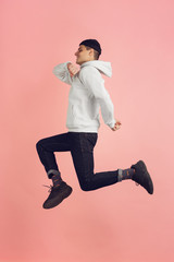 On the run. Caucasian young man's modern portrait isolated on pink studio background. Beautiful male model in high jump. Concept of human emotions, facial expression, sales, ad. Copyspace.