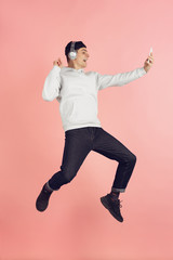Selfie, video call. Caucasian young man's modern portrait isolated on pink studio background. Beautiful male model in high jump. Concept of human emotions, facial expression, sales, ad. Copyspace.