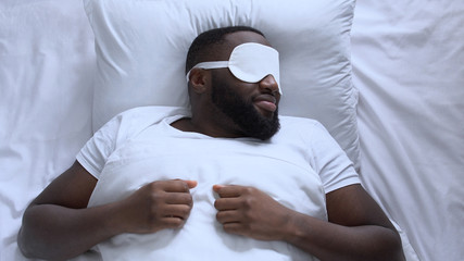 African american man putting mask on his eyes for better sleeping at night
