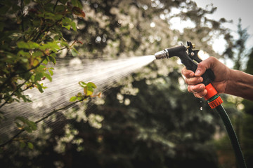 Watering garden equipment - hand holds the sprinkler gun for irrigation plants. Gardener hand with...