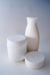 Jars of care products in white in various shapes and with different lids on a light background
