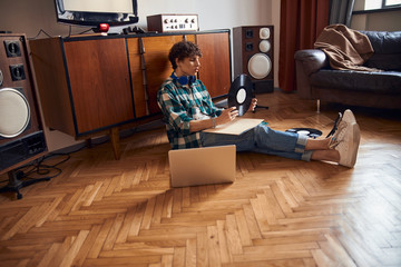 Attractive young man holding vinyl record while resting at home
