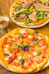 margherita pizza and a proscuitto and arugula pizza