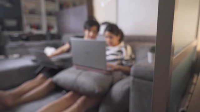 BLUR background Asian couple sit on the gray sofa helping each other working in living room apartment, life during home quarantine, discuss on the projects, together relationship goal, busy evening 4k
