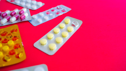 Close up of medical blister packs with tablets on pink background. Packs with various tablets. Concept of threat of various diseases.