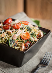 Miska makaronu spagetti z łososiem, szpinakiem, pomidorami koktajlowymi i suszonymi pomidorami