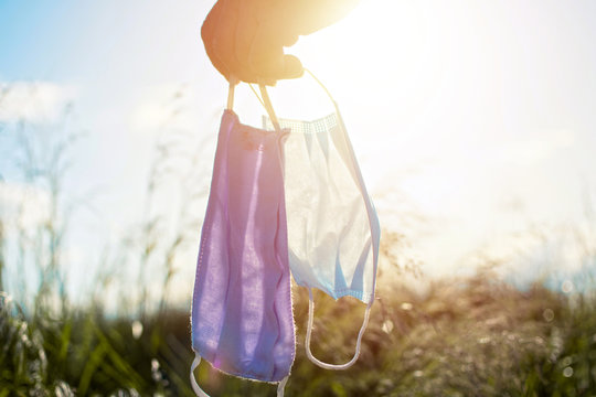 Man Hand Holding Mask, Protective Masks Against Sun Light. Concept Of Freedom During Covid 19. Positivity Through Quarantine Walking At Nature. End Covid.