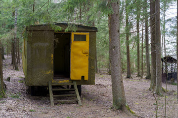 Old and abandoned iron trailer left to deteriorate in a forest among the pine trees.