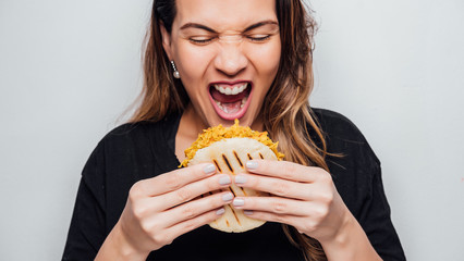Latin girl holds an arepa in her hands ready to eat it, Arepa stuffed with chicken