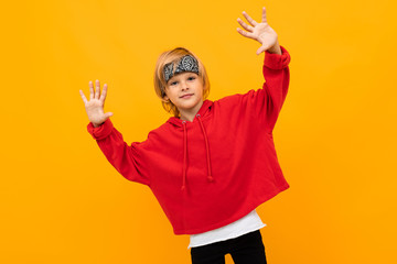Fototapeta na wymiar Stylish young boy in red sweatshirt and white t-shirt puts hands on his chest