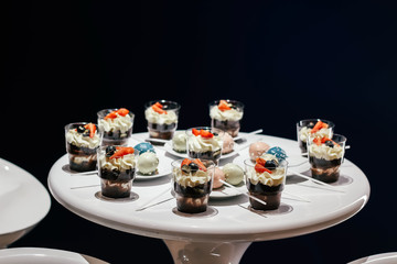 Desserts with whipped cream and strawberries on a white table. Glamorous style