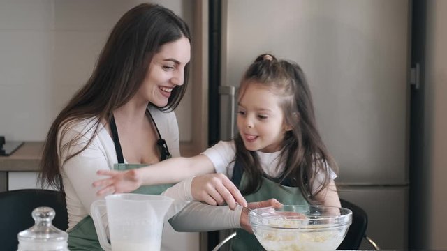 A pretty mother and daughter are making pastry for cookies. The kid and parent are celebrating Mother's day.