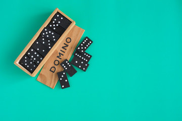 Domino game in wooden box on green  background, top view. Family table game