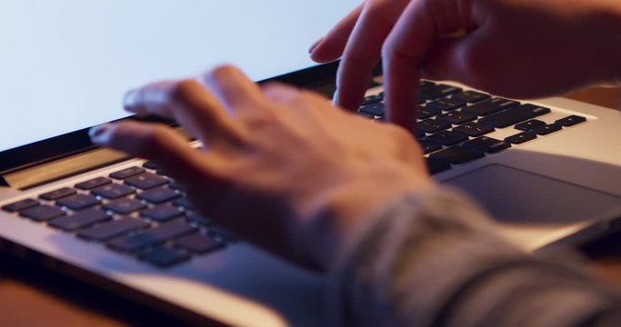 Female student typing essay on laptop computer late at home