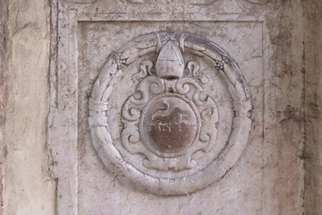 Bas-relief on one of the walls of Cracow. Old coat of arms with a lion and a papal tiara.
