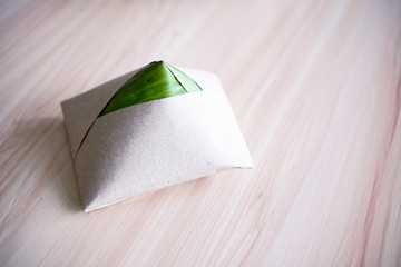 Teh tarik with nasi lemak pack in banana leaf in background, popular breakfast in Malaysia.