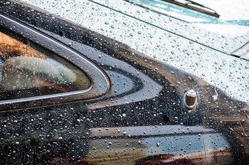 Multiple waterdrops on a new black car parked in the city
