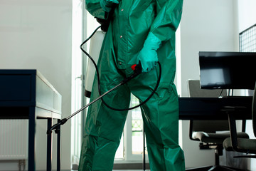 Person in hazmat suit cautiously sanitizing the room stock photo