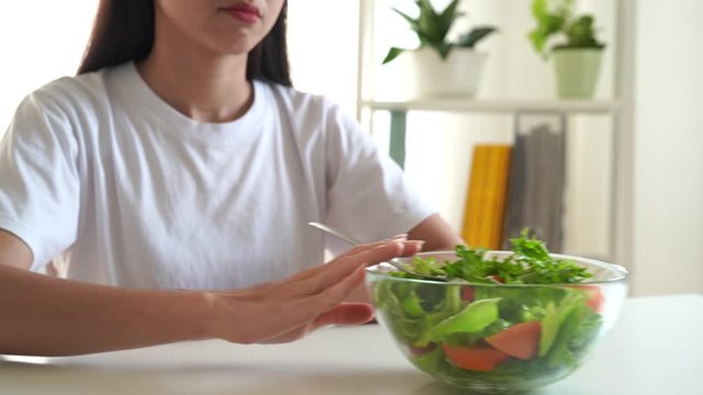 The unhappy dieting Asian girl has a boring expression, She doesn't like to eat vegetables, Health and vegetarian concepts.